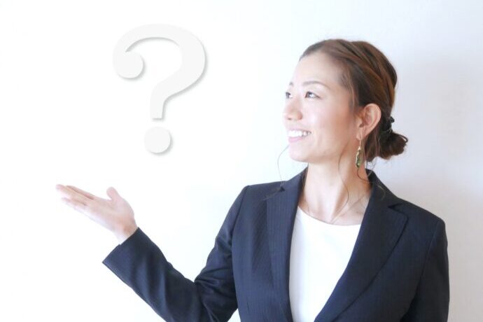 画像:はてなマークを浮かべるスーツの女性