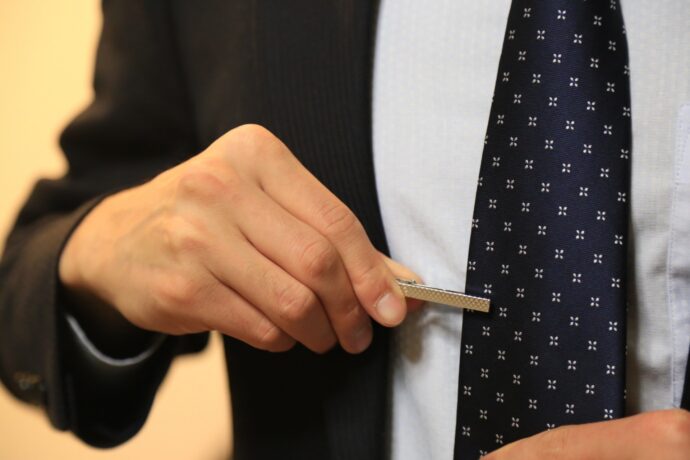 画像：ネクタイピンを挿す男性