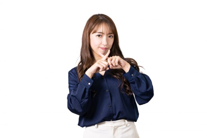 画像：顔の前で×を作る女性