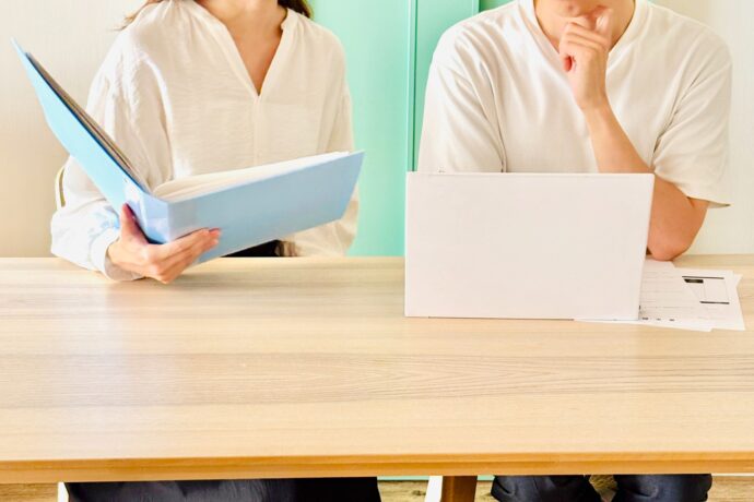 画像：パソコンと名簿を覗き込む男女