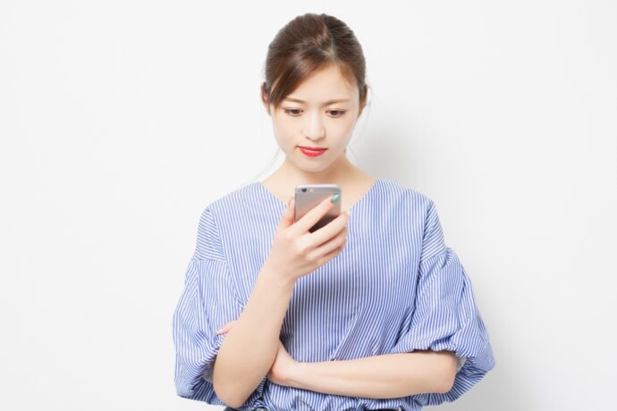 画像：スマホを見て渋い顔を作る女性