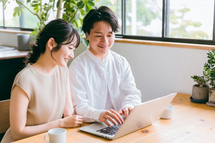 画像：パソコンを覗き込む若い男女