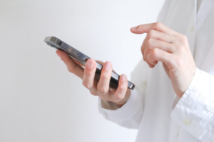 画像：スマホを操作する男性の手元